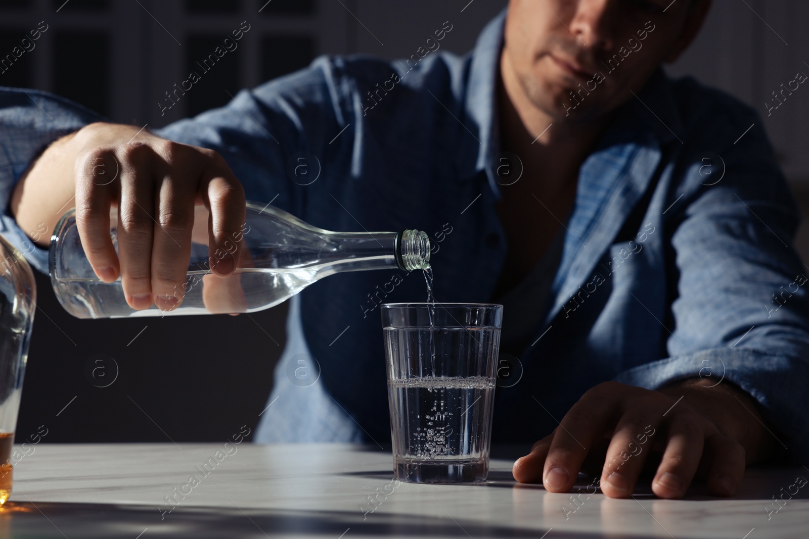 Photo of Addicted man with alcoholic drink at table in kitchen, closeup