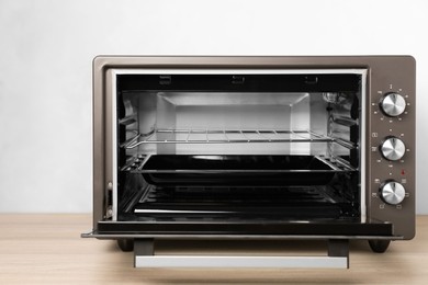 Photo of One electric oven on wooden table near light blue wall