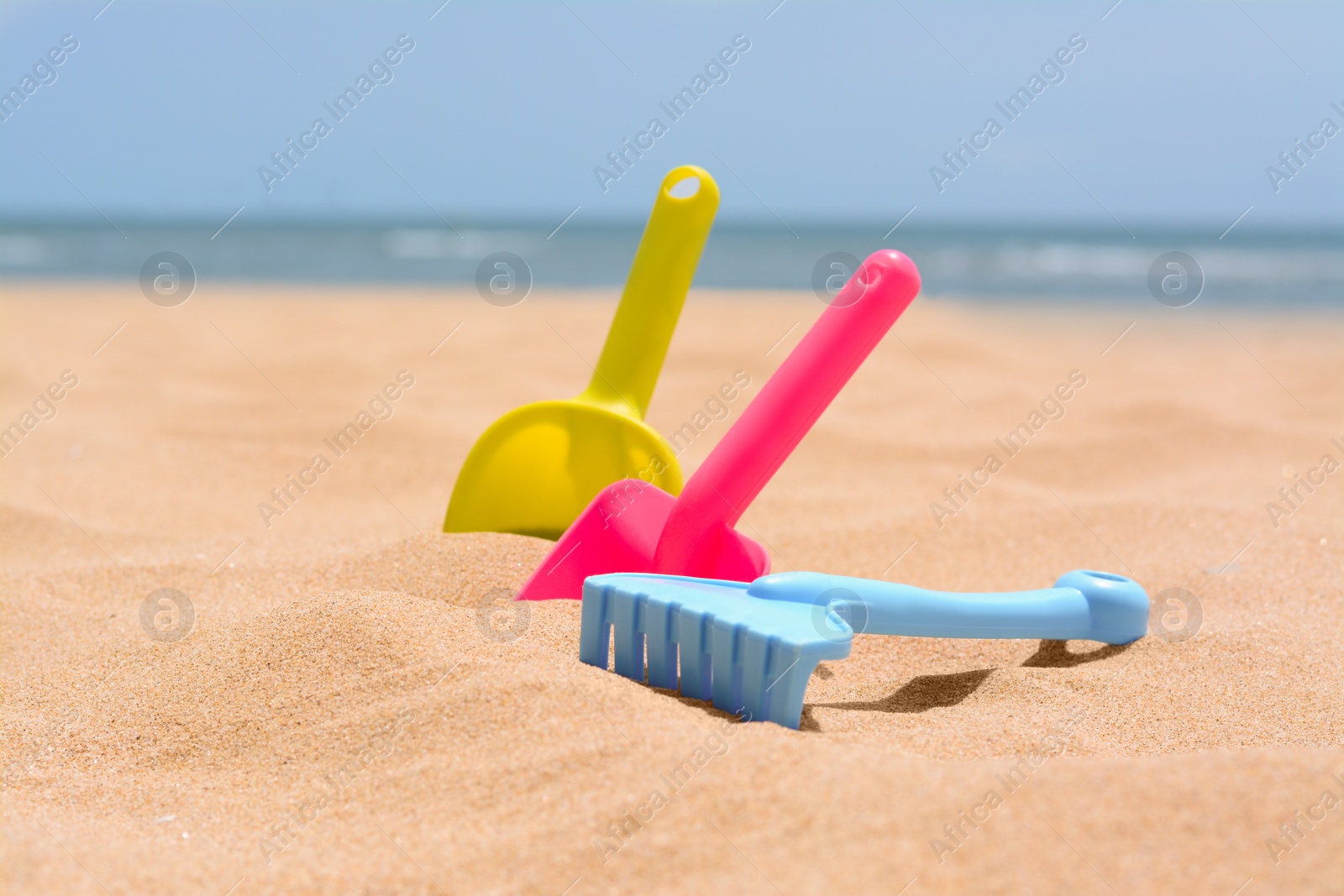 Photo of Set of colorful beach toys on sand near sea