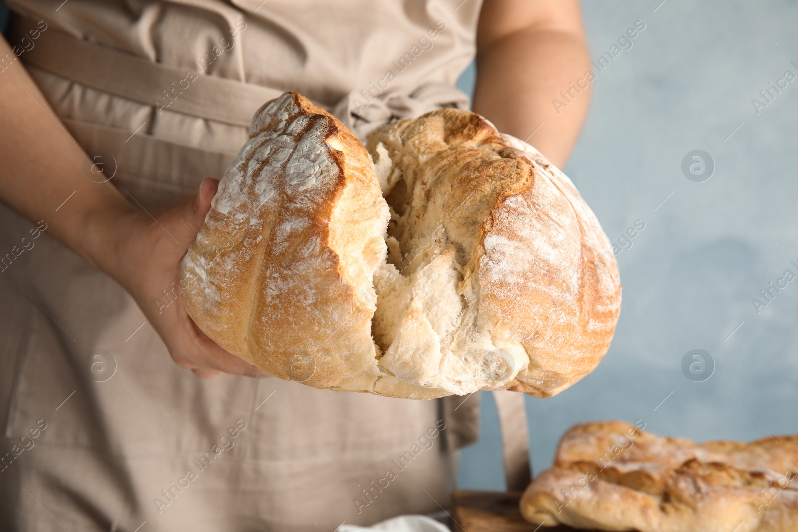 Photo of Man holding whole wheat bread on color background, closeup