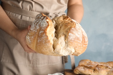 Photo of Man holding whole wheat bread on color background, closeup