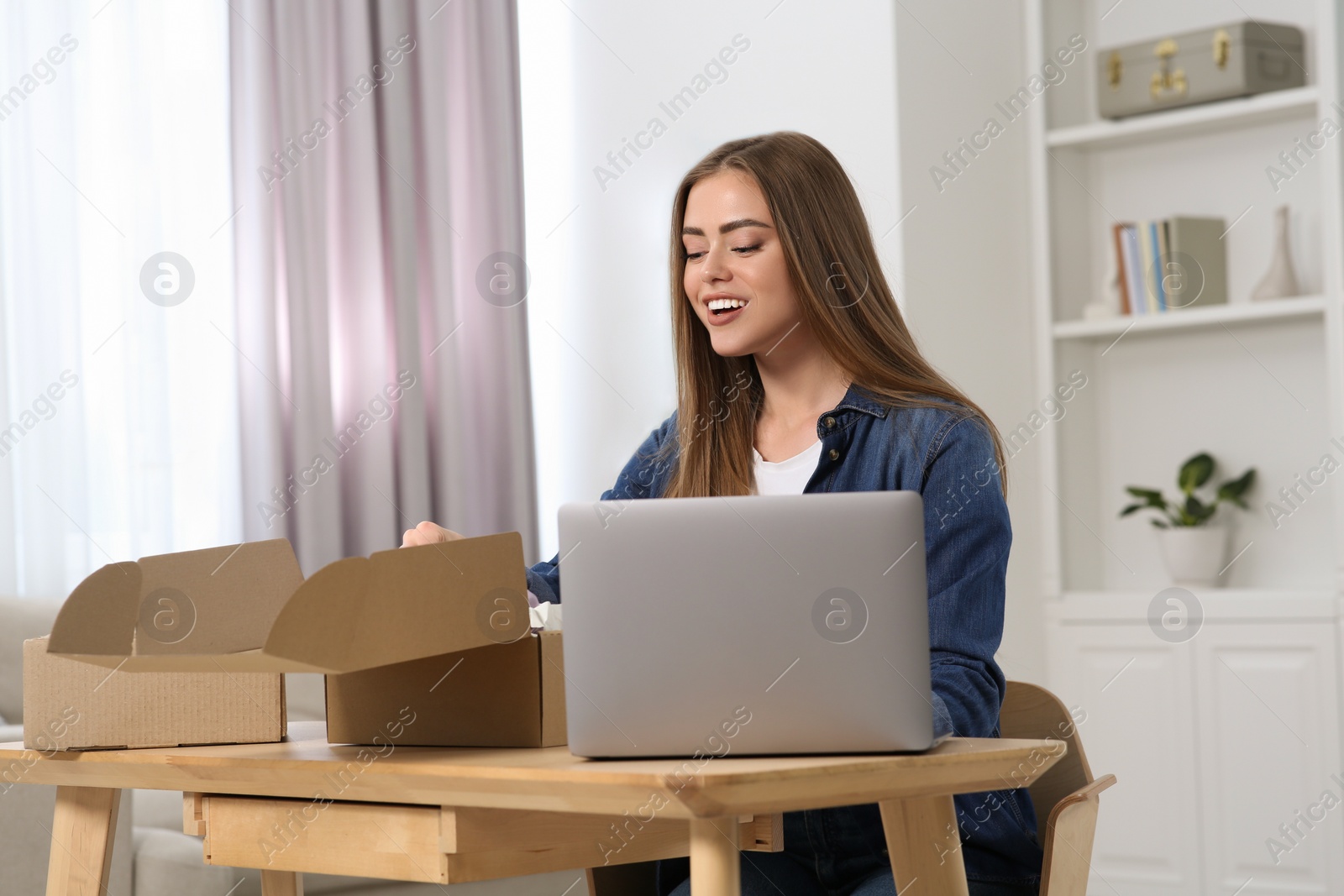 Photo of Happy woman unpacking parcel at home. Online store