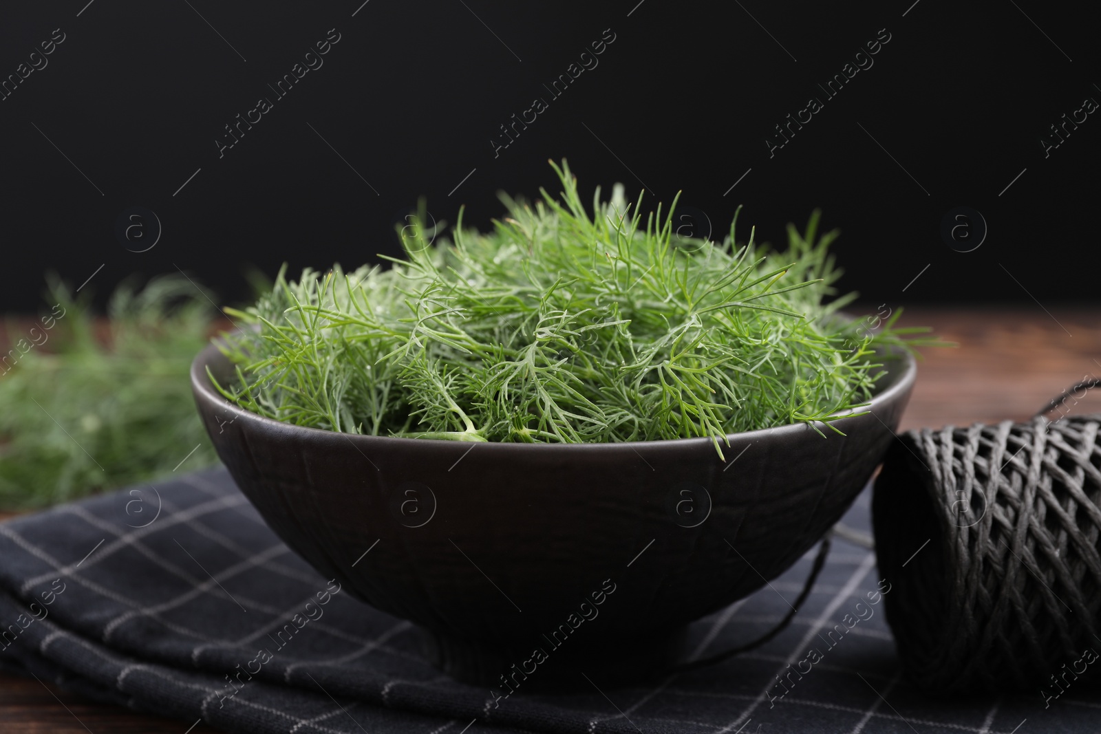 Photo of Bowl of fresh dill and spool of thread on table