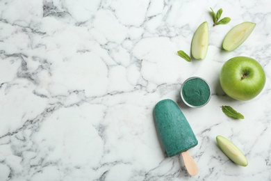 Photo of Flat lay composition with delicious spirulina popsicle on marble table. Space for text