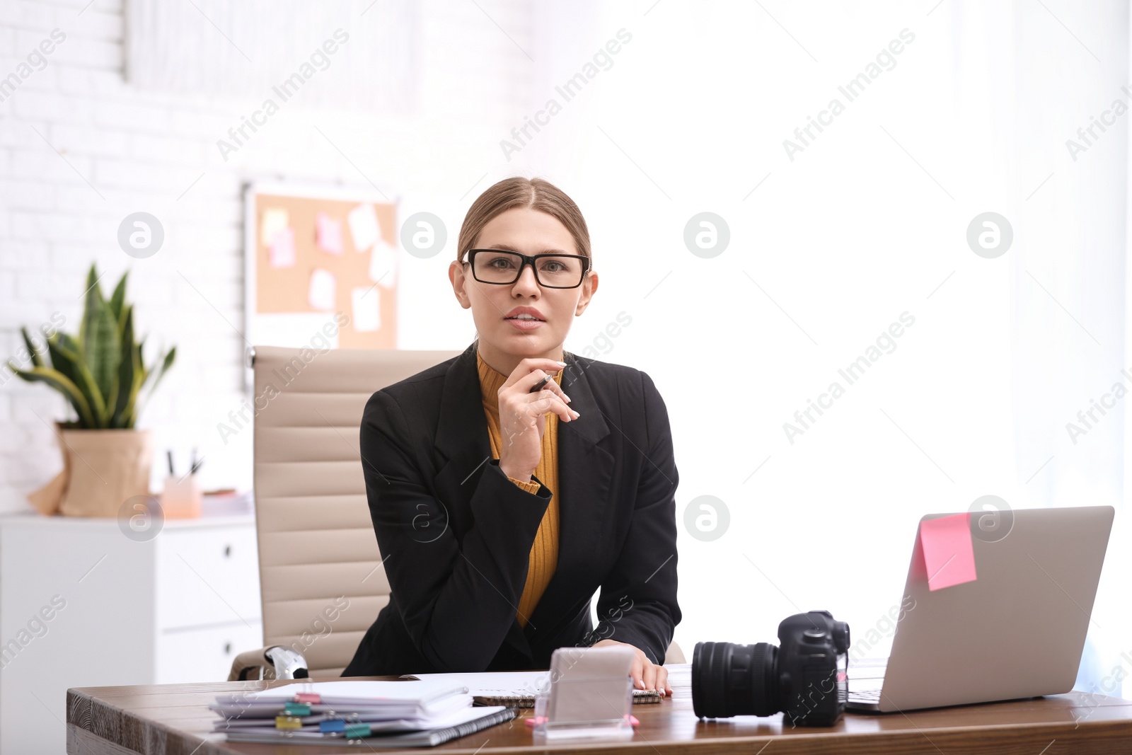 Photo of Young journalist working at table in office