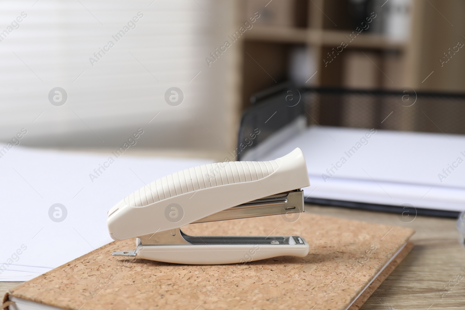 Photo of Stapler and notebook on wooden table indoors, closeup