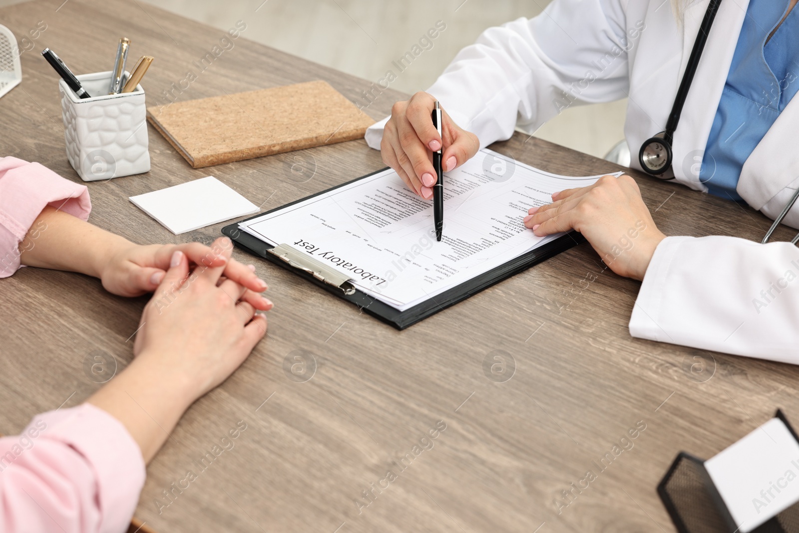 Photo of Doctor with results of laboratory test consulting pregnant patient in clinic, closeup