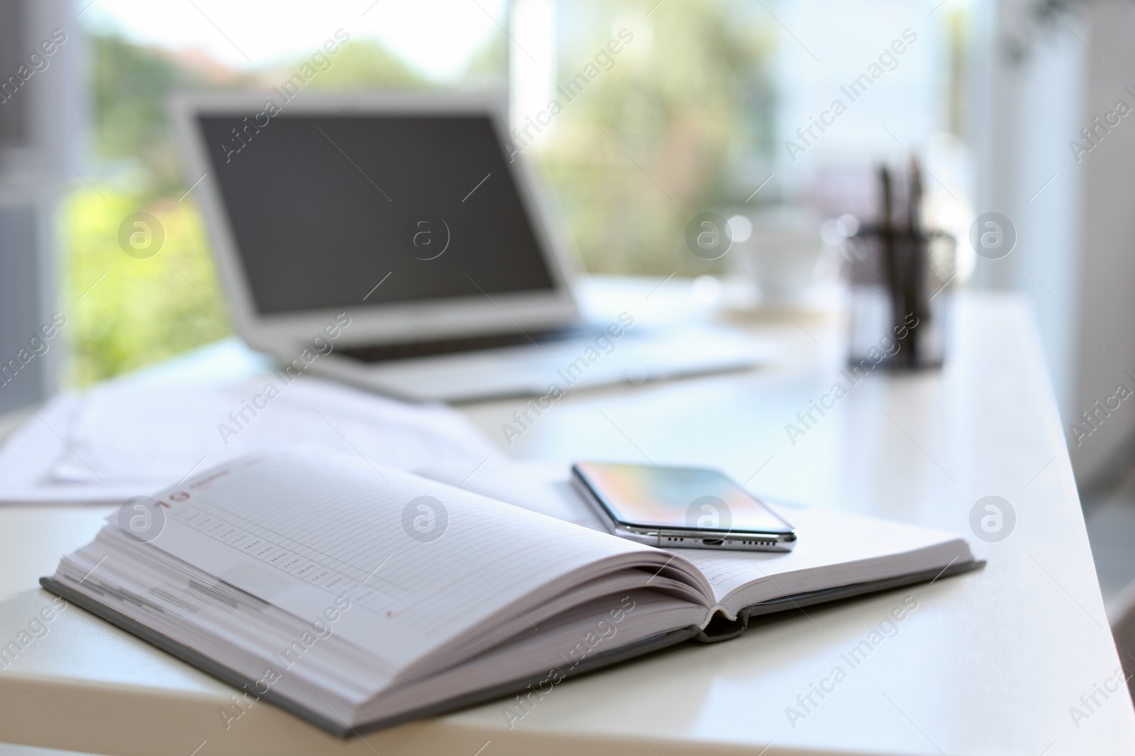 Photo of Planner and modern smartphone on table in office