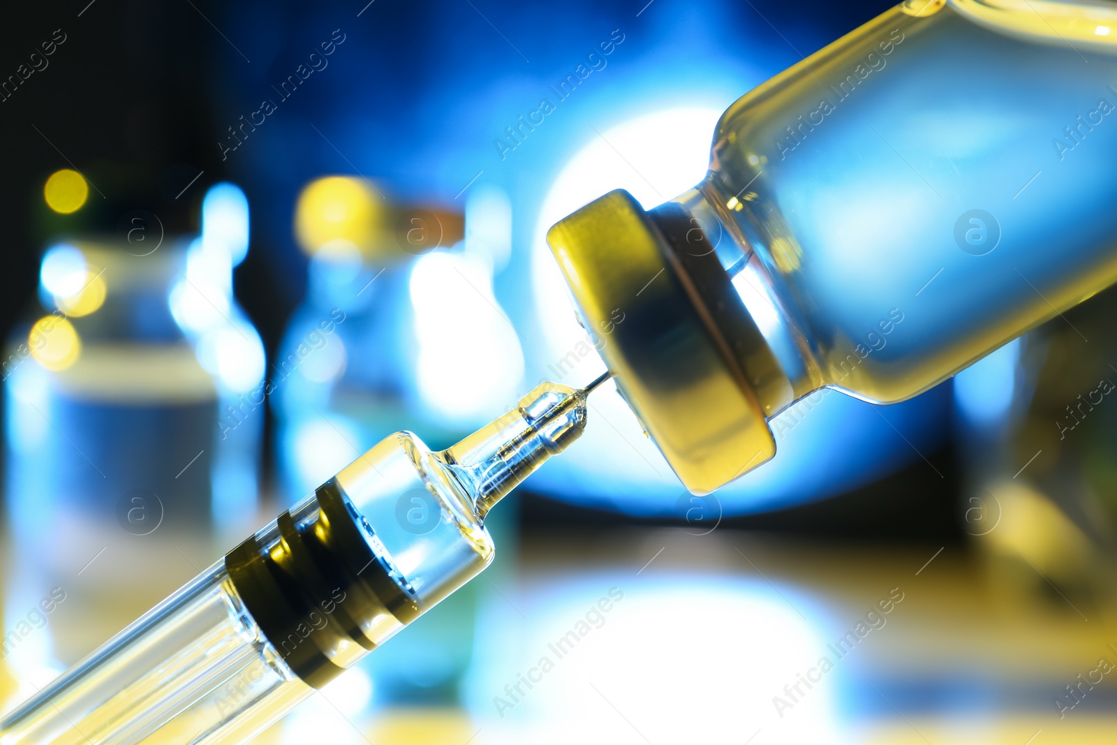 Photo of Filling syringe with vaccine from vial on blurred background, closeup