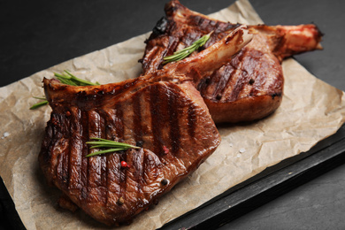 Photo of Delicious beef steaks with rosemary on black table, closeup