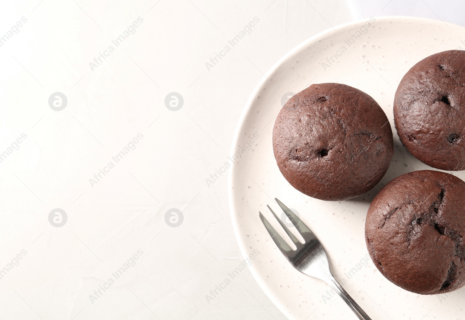 Photo of Delicious chocolate cupcakes on white table, top view. Space for text