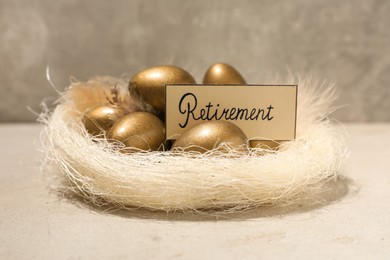 Photo of Golden eggs and card with word Retirement in nest on light table. Pension concept