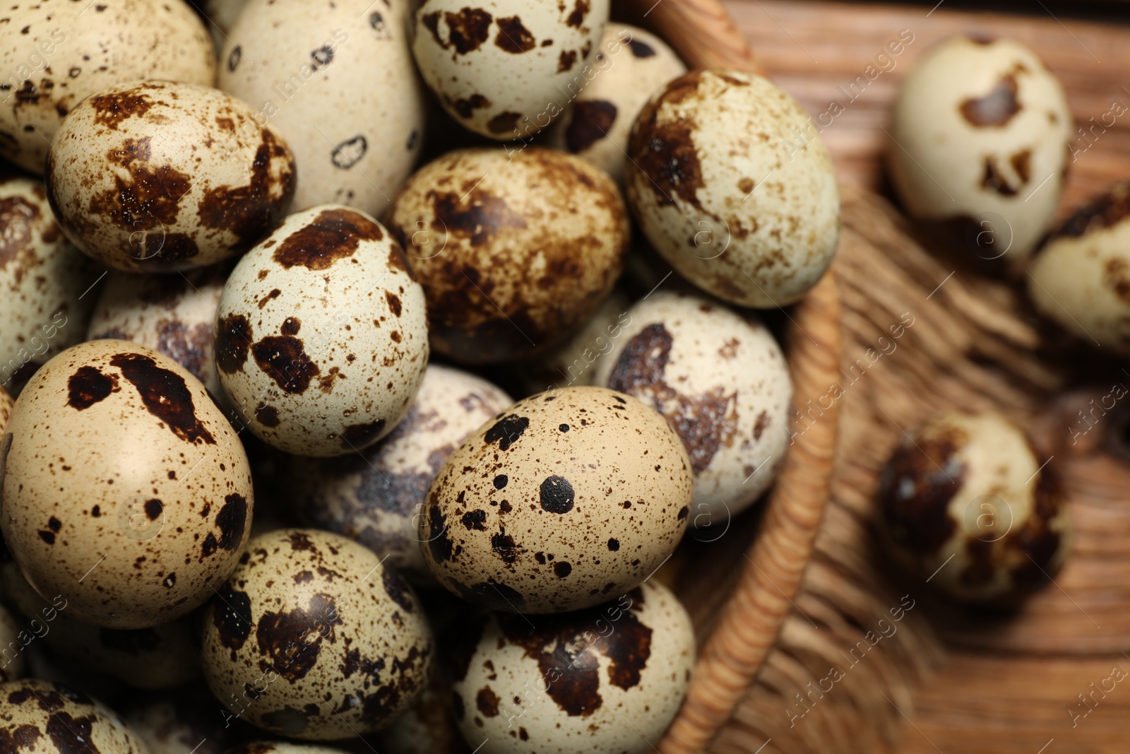 Photo of Wooden bowl with quail eggs on table, closeup