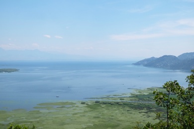 Image of Picturesque view of beautiful bay near mountains under blue sky with clouds