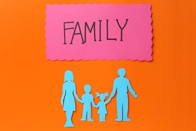 Photo of Card with text Family and paper cutout on orange background, flat lay