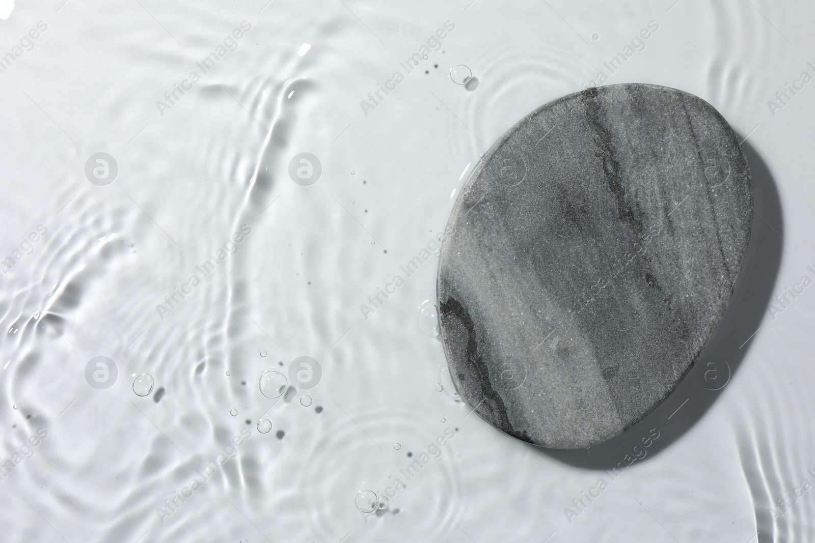 Photo of Presentation of product. Stone podium in water on white background, top view. Space for text