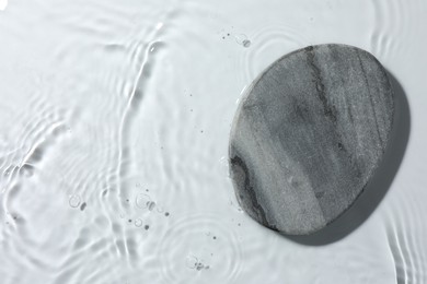 Photo of Presentation of product. Stone podium in water on white background, top view. Space for text