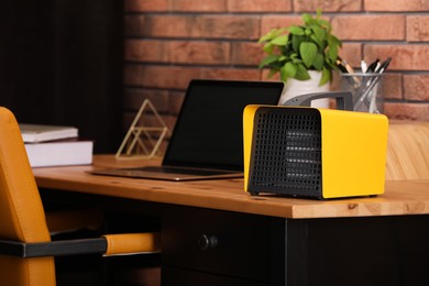 Photo of Modern electric heater near laptop on wooden table in office