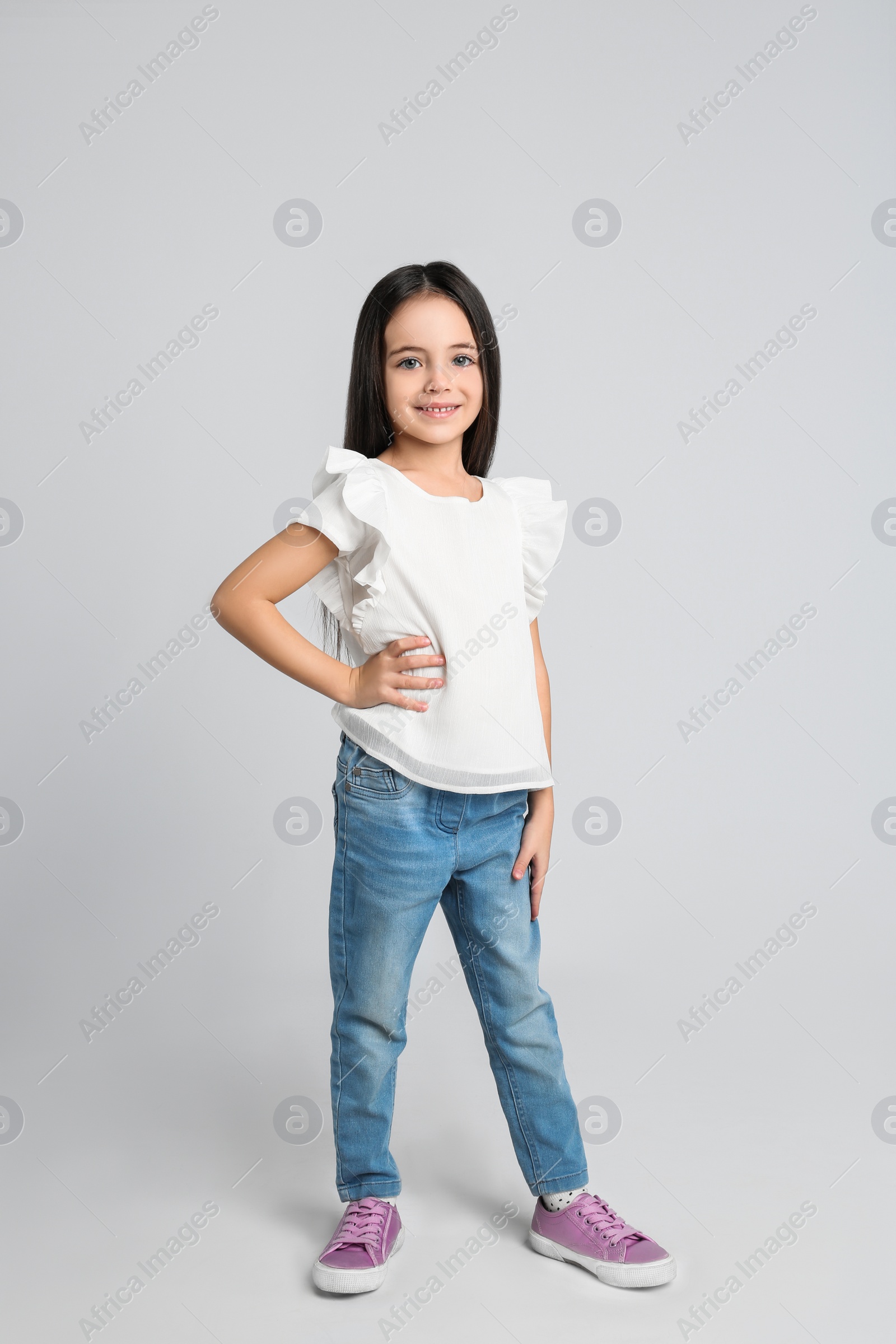 Photo of Cute little girl posing on light grey background