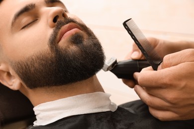 Photo of Professional hairdresser working with client in barbershop, closeup