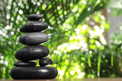 Photo of Stack of stones and blurred green leaves on background, space for text. Zen concept