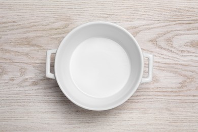 Photo of One empty pot on white wooden table, top view