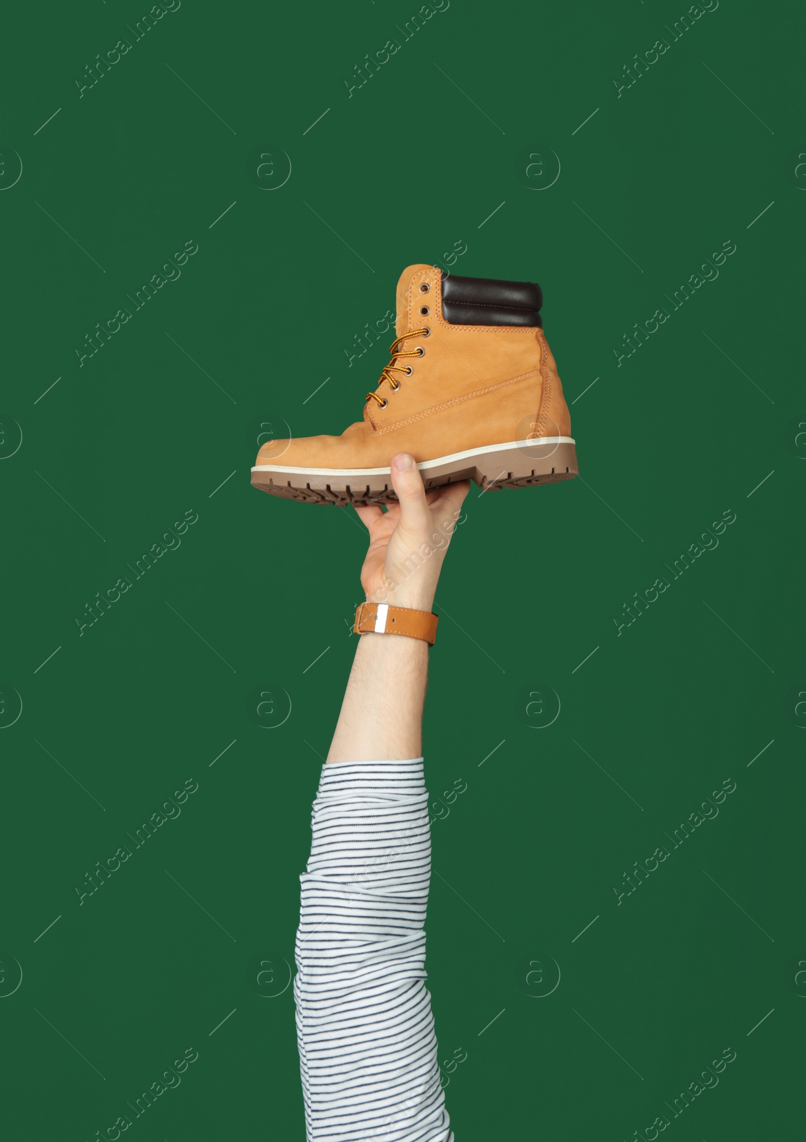 Photo of Man holding stylish shoe on green background, closeup