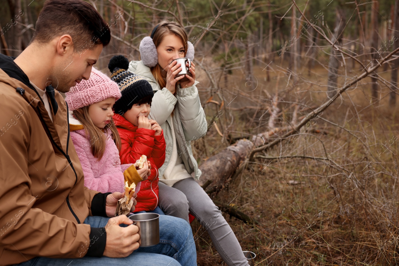 Photo of Happy family with sandwiches and hot drinks spending time together in forest