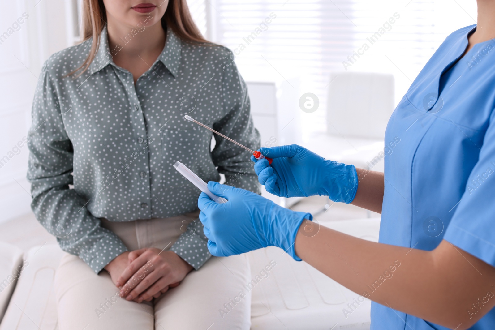 Photo of Doctor taking sample for STD testing from woman in clinic, closeup