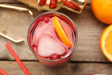 Photo of Tasty cranberry cocktail with ice cubes and orange in glass on wooden table, above view