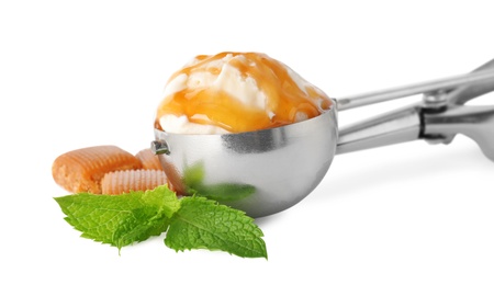 Metal scoop with delicious ice cream, mint and caramel candies on white background