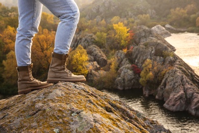 Woman wearing stylish hiking boots on steep cliff, closeup