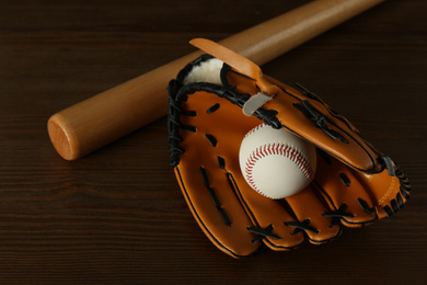 Photo of Leather baseball ball, bat and glove on wooden table
