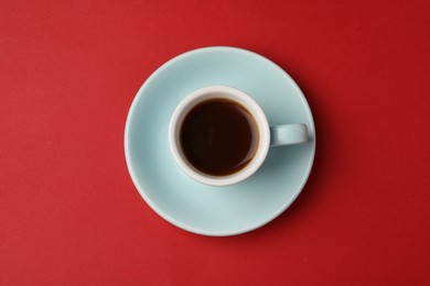 Tasty coffee in cup on red background, top view