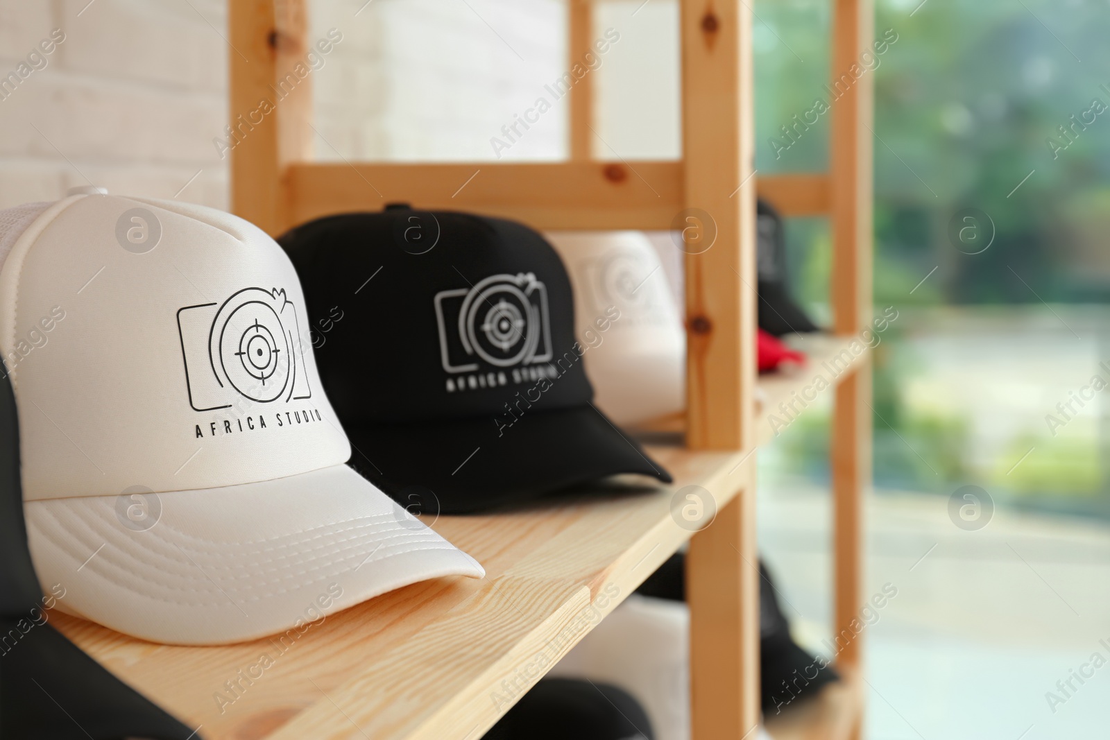 Photo of Different caps with logo on wooden shelf in shop