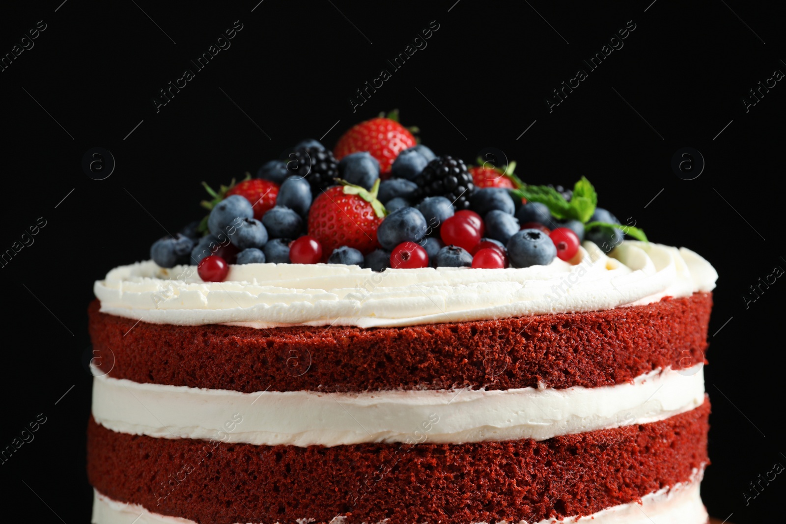 Photo of Delicious homemade red velvet cake with fresh berries on black background, closeup