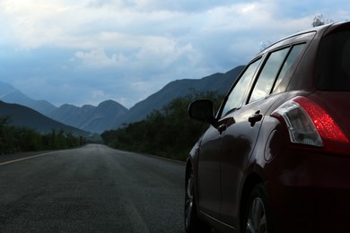 Beautiful view of mountains and car on asphalt highway outdoors, closeup. Road trip