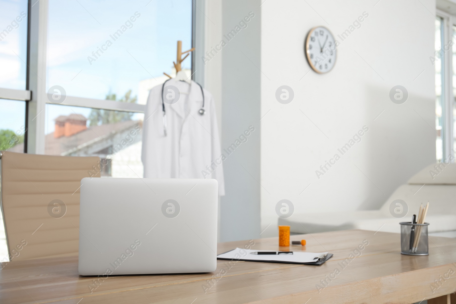 Photo of Modern laptop on wooden table in medical office, space for text. Interior design