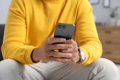 Photo of Man sending message via smartphone indoors, closeup