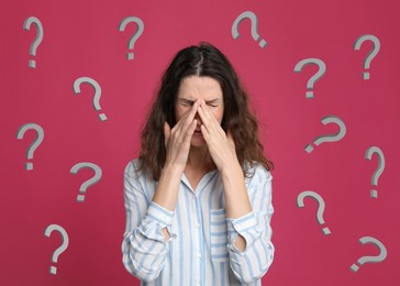 Image of Amnesia. Confused woman and question marks on pink background