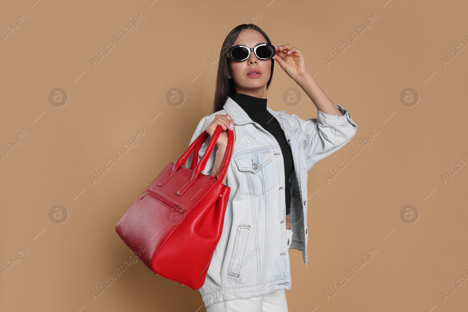 Photo of Young woman with stylish bag on beige background