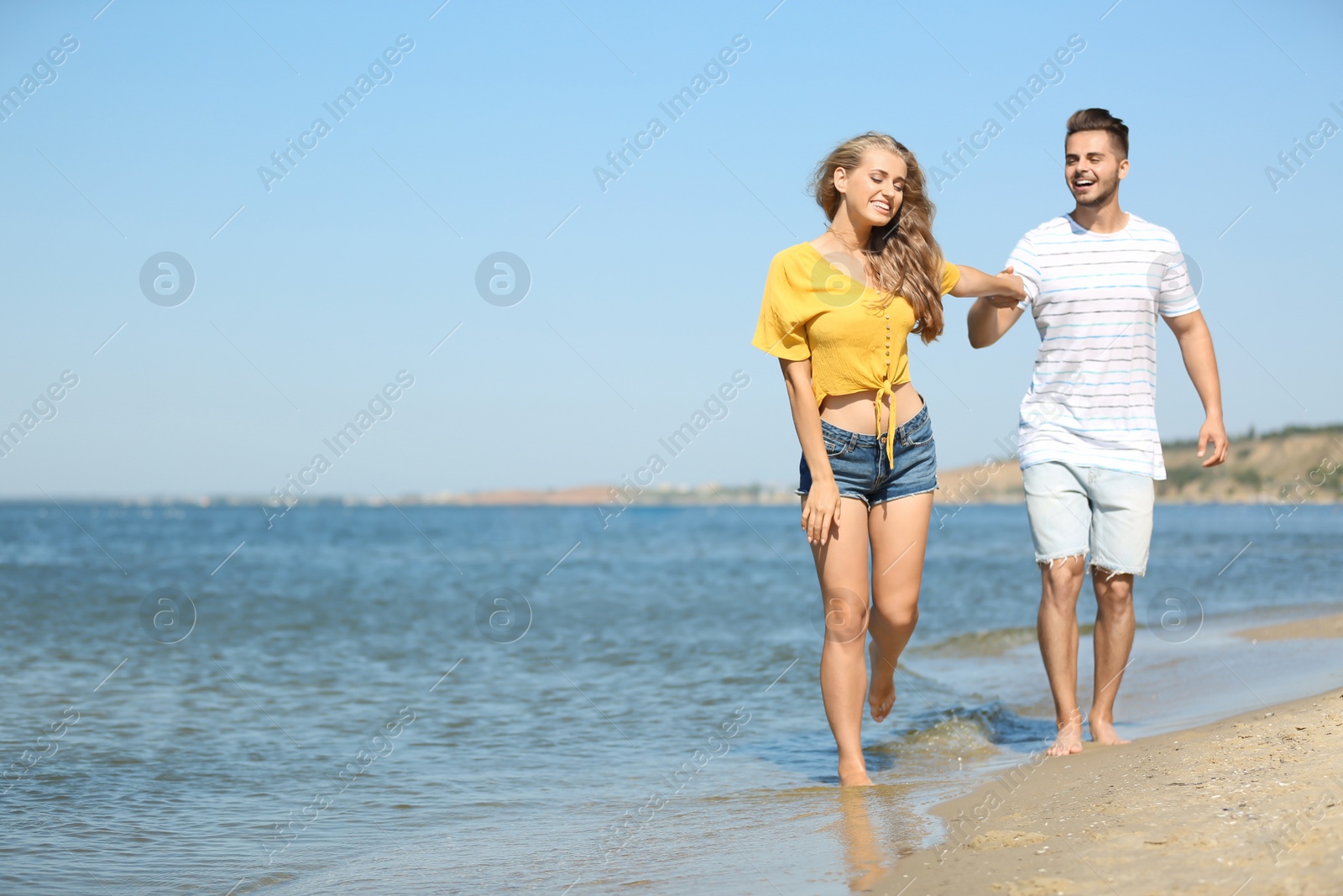 Photo of Happy young couple walking at beach on sunny day