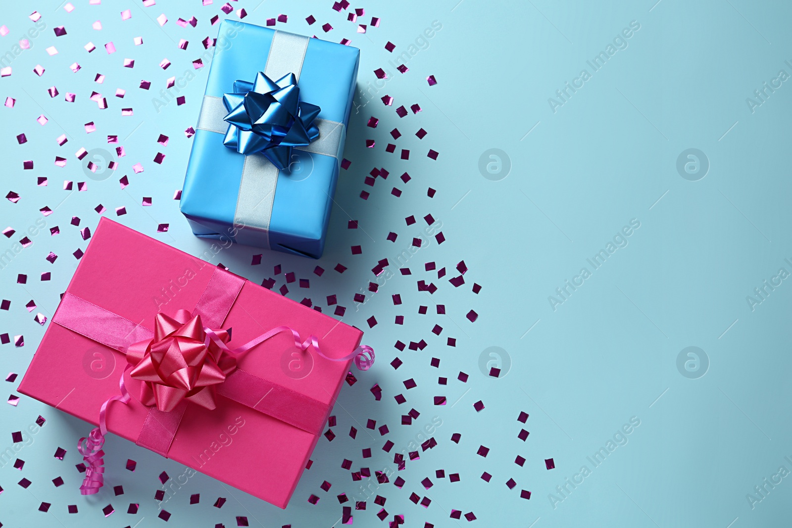 Photo of Gift boxes and shiny confetti on light blue background, flat lay. Space for text