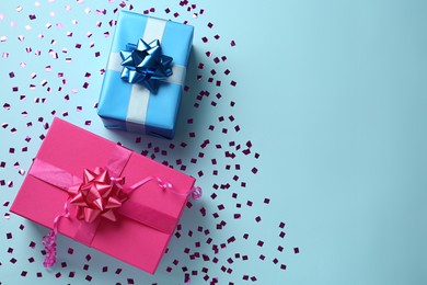 Gift boxes and shiny confetti on light blue background, flat lay. Space for text