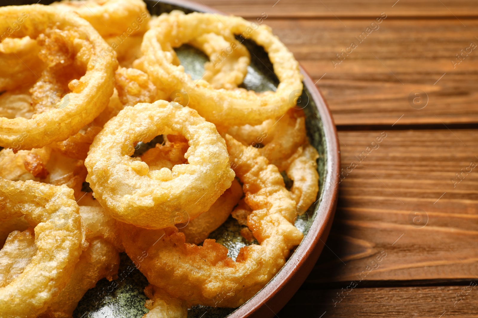Photo of Homemade crunchy fried onion rings on wooden table, closeup
