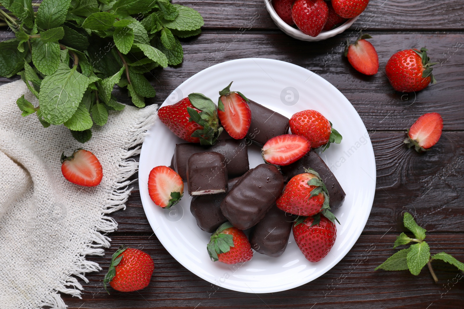 Photo of Delicious glazed curd snacks, mint leaves and fresh strawberries on wooden table, flat lay