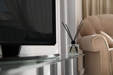 Photo of Aromatic reed air freshener on tv table at home, space for text