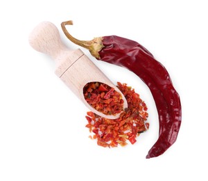 Photo of Aromatic spice. Red chili pepper flakes in scoop and pod isolated on white, top view