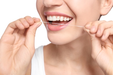 Photo of Young woman flossing her teeth on white background, closeup