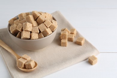 Photo of Brown sugar cubes on white wooden table, space for text